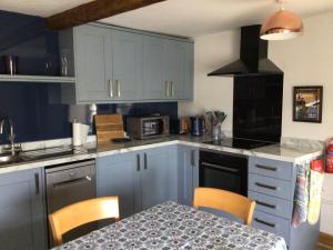 a kitchen with blue cabinets and a table with chairs at Victoria Cottage in Reeth