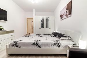 a white bedroom with a bed and a tv at URBAN LUXURY in Constanţa