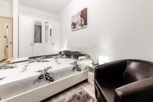 a white bedroom with a bed and a chair at URBAN LUXURY in Constanţa