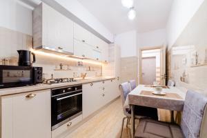 a kitchen with white cabinets and a table with chairs at URBAN LUXURY in Constanţa