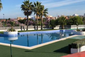 basen z palmami i miasto w tle w obiekcie Isla Canela Sea & Sun Golf - Ayamonte w mieście Ayamonte
