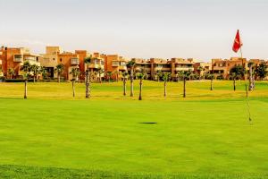 a golf course in front of a resort with palm trees at Modern Lakeview Apartment With Private Garden in Marrakesh