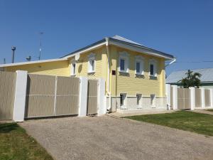 a yellow house with a white fence in front of it at Pokrovsky Guest House in Suzdal