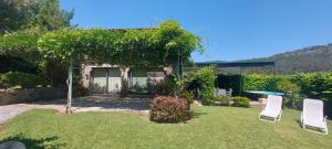 un patio con 2 sillas blancas y una casa en Casas da Tapada Briteiros Casa Do Espigueiro, en Guimarães