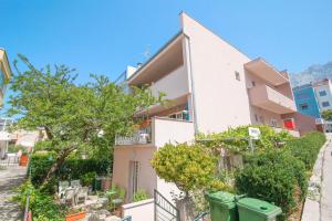 an apartment building with two green trash cans in front of it at Studio apartment Laura-spacious studio on the main beach in Makarska