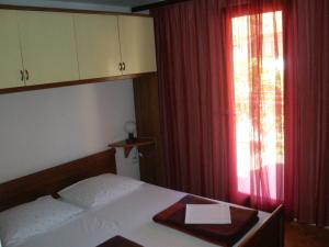 een slaapkamer met een bed en een raam met rode gordijnen bij Apartment Borik in Zadar