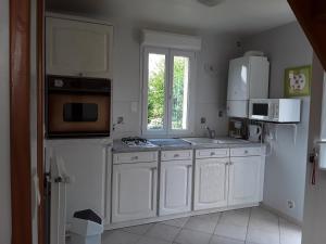 une cuisine avec des placards blancs et une fenêtre dans l'établissement Maison( Clesanie ), 