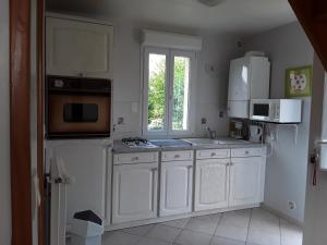a kitchen with white cabinets and a window at Maison( Clesanie ) in Serquigny