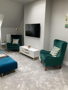 a living room with two green chairs and a tv at The Loft, Bootham House - luxury city centre apartment with parking space in York