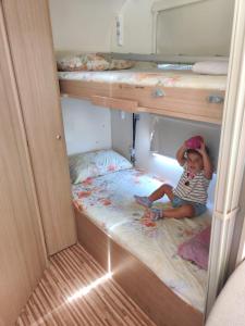 a young child sitting in the middle of a bunk bed at Caravan In the Desert in Eilat