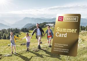 a family walking on a hill with a sign for summer card at Hotel Felsenstüberl in Sölden