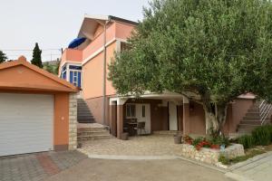 una casa con un árbol delante de ella en Apartman Olive 01, en Zadar