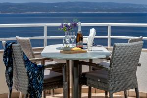 - une table avec une bouteille de vin et des fleurs sur le balcon dans l'établissement Apartments Vranjes, à Brela