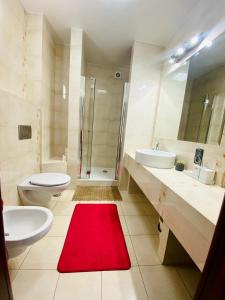 a bathroom with two sinks a toilet and a red rug at Apartament in Szczytno