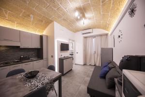 a kitchen and a living room with a couch and a table at Amare Cefalù - Elegant Apartment in Cefalù