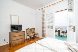 Un dormitorio con una cama, un televisor y una mesa. en Apartments Kazo, en Dubrovnik
