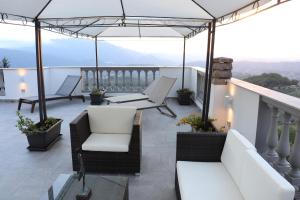 balcón con sofás, sillas y sombrilla en Villa Inglese, en Picinisco