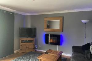 a living room with a couch and a tv and a table at Small family home in idyllic location in Buriton