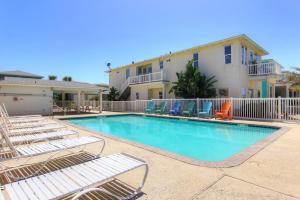 a swimming pool with lounge chairs and a building at Popsicles and Flip Flops VW8 in Port Aransas
