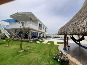 een groot wit huis met een grasdak bij Cabaña Villa Carmen in Juan de Acosta