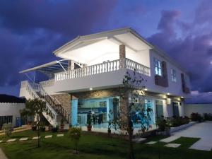 uma casa branca com uma varanda em cima em Cabaña Villa Carmen em Juan de Acosta