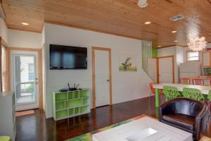 ein Wohnzimmer mit einem Tisch und einem Fernseher an der Wand in der Unterkunft Harpers Berry 5SC in Port Aransas