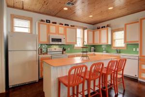 eine Küche mit einem Kühlschrank und einer Theke mit Stühlen in der Unterkunft Harpers Berry 5SC in Port Aransas
