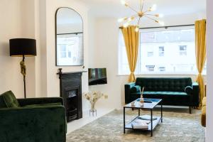 un salon avec deux canapés verts et une cheminée dans l'établissement Chic Beach Getaway (sleeps 6) - 4min walk to beach, à Kent