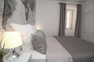 um quarto com uma cama com almofadas brancas e um candeeiro em Carrera Corner Apartment em Rovinj