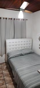 a bed with a white headboard in a bedroom at chalé do Radiola in Ilhabela