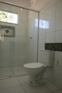 a white bathroom with a toilet and a shower at Chalés Magia Da Lua in Cavalcante