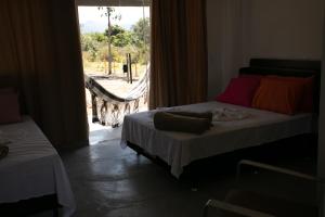a bedroom with two beds and a large window at Chalés Magia Da Lua in Cavalcante