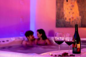 un hombre y una mujer en una bañera con copas de vino en Hotel Dusseldorf, en Rímini