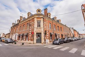 un vieux bâtiment en briques dans une rue avec des voitures garées dans l'établissement Suite PREMIUM LE FIGARO 2, à Épernay