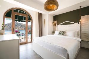 a bedroom with a white bed and a large window at Liman Hotel Gümüslük - Adult Only in Bodrum City