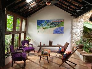 sala de estar con sillas, mesa y una pintura en Pousada Arte Urquijo en Paraty