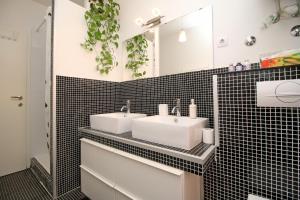 uma casa de banho em azulejos pretos com 2 lavatórios e um espelho. em Carrera Corner Apartment em Rovinj
