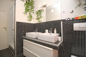 a black tiled bathroom with two sinks and a mirror at Carrera Corner Apartment in Rovinj