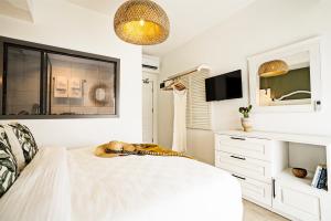 a white bedroom with a bed and a tv at Liman Hotel Gümüslük - Adult Only in Bodrum City