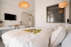 a white bedroom with a bed and a tv at Liman Hotel Gümüslük - Adult Only in Bodrum City
