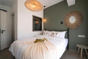a bedroom with a large white bed with a round mirror at Liman Hotel Gümüslük - Adult Only in Bodrum City