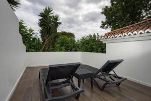 a patio with two chairs and a table on a white wall at Senhora da Rosa, Tradition & Nature Hotel in Ponta Delgada