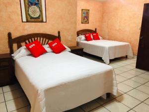 two beds in a room with red pillows on them at Hotel Fernando´s in Tlalpujahua de Rayón