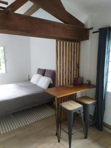 1 dormitorio con 1 cama, mesa de madera y sillas en Les gîtes des Beaux Chênes, en Mortagne-sur-Sèvre