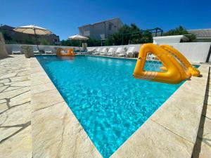 a swimming pool with a yellow slide in the water at Apartments King - City center in Novalja