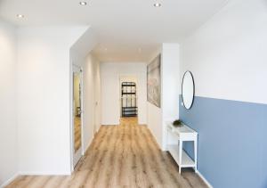 a hallway with white walls and wood floors and a mirror at Prachtig appartement in het centrum van Yerseke in Yerseke