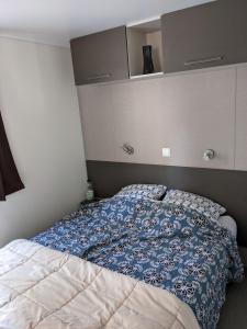 a bedroom with a bed with a blue comforter at Mobil home Stéfie in Vias