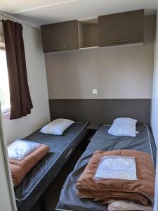 two beds in a small room with a window at Mobil home Stéfie in Vias