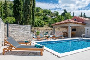 a pool with lounge chairs and a gazebo at Villa Pajkan in Dubrovnik