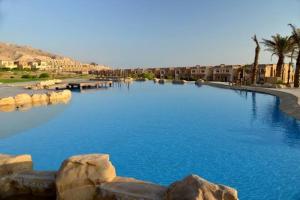 a large pool of blue water with palm trees and buildings at Chalet in Telal Alsokhna resort - Unit 3072b in Ain Sokhna